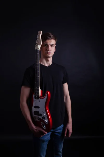 Joven caucásico adulto sosteniendo la guitarra en el estudio —  Fotos de Stock