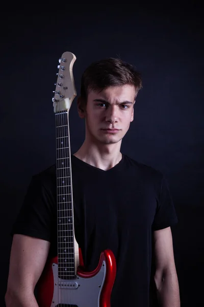 Young caucasian adult holding guitar in the studio