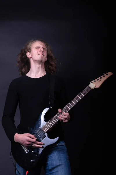 Young caucasian adult playing guitar in the studio