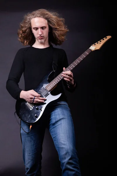 Young caucasian adult playing guitar in the studio