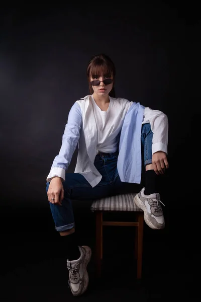 Кавказька дівчина в білій сорочці з чорними сонцезахисних окулярів позує в студії — стокове фото