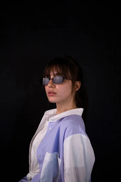 Кавказька дівчина в білій сорочці з чорними сонцезахисних окулярів позує в студії — стокове фото