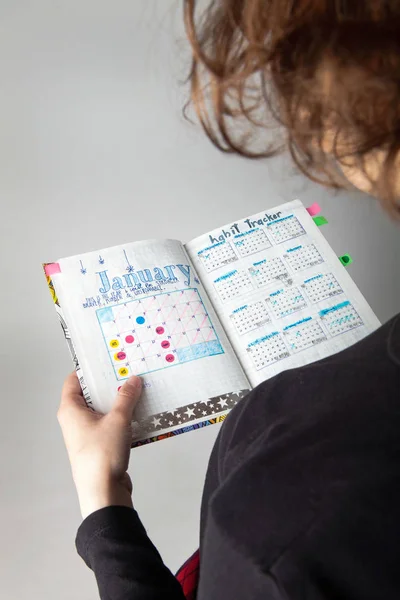 Junges kaukasisches lockiges Mädchen liest Bullet Journal hören — Stockfoto