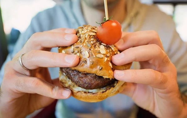 Ein Mann hält einen Burger in der Hand — Stockfoto