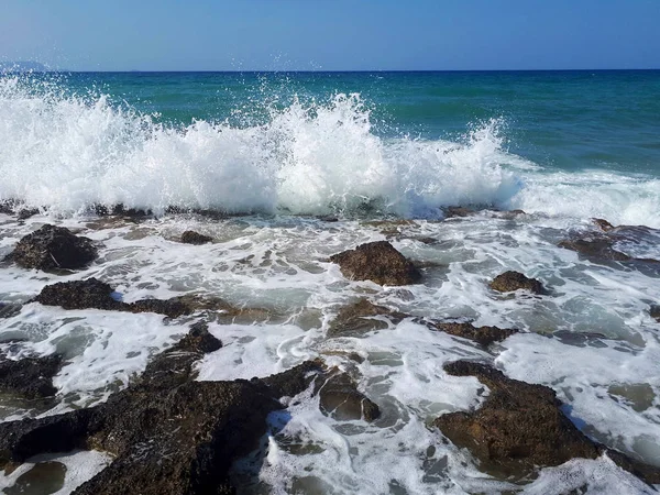 Vattenstänk vid havet och stranden med blå himmel — Stockfoto