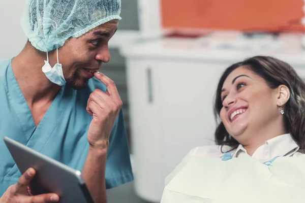 Dentista mostrando a su paciente una imagen en un dispositivo electrónico — Foto de Stock
