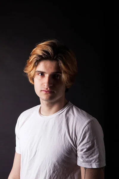 Молодой кавказский взрослый с окрашенными светлыми волосами, позирующий на черном — стоковое фото