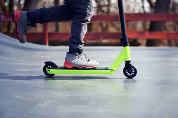 Kid riding on stunt scooter on the skatepark ramp