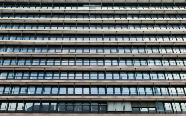 A fachada de um edifício de escritórios com muitas janelas dispostas em uma linha , — Fotografia de Stock