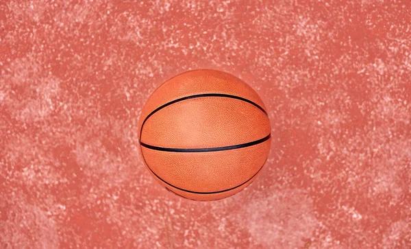 Basketball laying on red ground