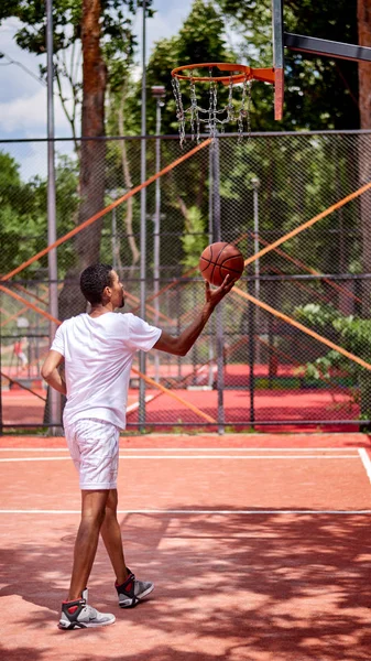 Черный баскетболист держит забор звеном цепи руками — стоковое фото