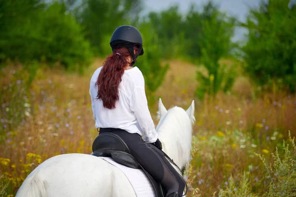 Fille en tenue équestre chevauchant un cheval près des arbres — Photo