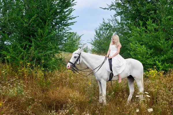 Fille en robe blanche chevauchant un cheval dans le champ — Photo