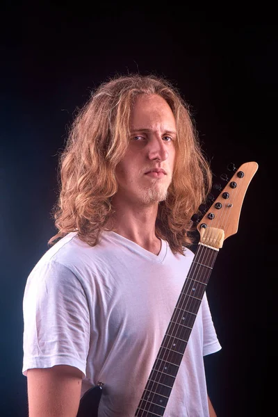 Caucasian man with blonde hair holding his black guitar