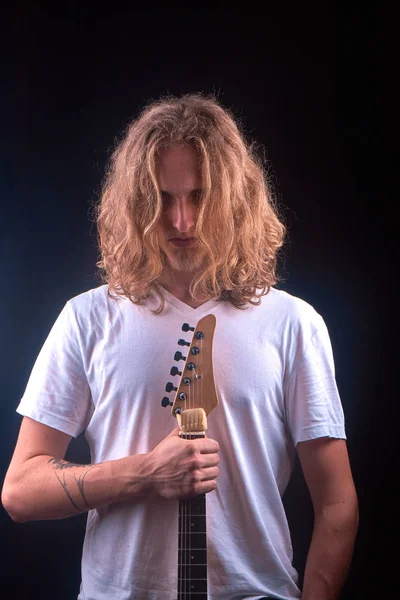 Белый мужчина с светлыми волосами держит черную гитару — стоковое фото
