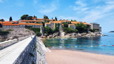 Sveti Stefan Yarımadası 'na giden köprü, Karadağ' da suda demirli tekneler.