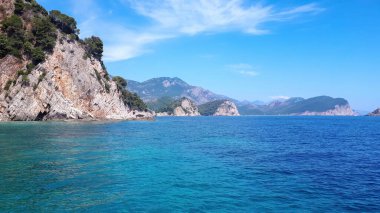 Adriyatik Denizi 'nin kayalık kıyıları, mavi sulara yakın uçurumlar ve Karadağ' ın Petrovac kentindeki yeşilliklerle kaplı tepeler