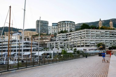 Monako, Monako - 13 Eylül 2019: Bir rıhtımdan, yürüyen ve oturan insanlardan, heykellerden ve arka plandaki binalardan görüntü