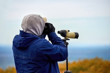 Massachusetts, ABD 'de kapüşonlu bir adam dürbünle bakıyor.
