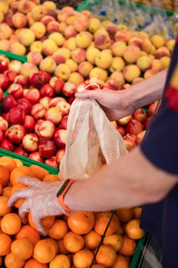 Süpermarkette mandalina alan bir adam.