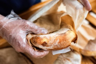 Süpermarkette plastik eldivenli bir adam fırın ürünleri alıyor, ekoloji fikri.