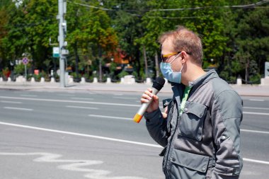 CHISINAU, MOLDOVA - 17 Temmuz 2020: Motosikletliler toplantısında mikrofonlu tıbbi maskeli adam, arka planda park