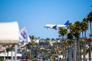 Açık havada uçan uçak, güneşli bir gün, San Diego, ABD 'de ağaçlar ve binalar.