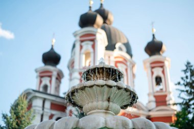Curchi manastırı manzaralı çeşme, ön planda ağaçlar ve kilise, Moldova