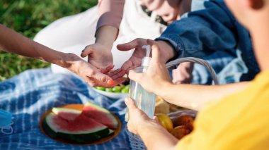 Moldova, Chisinau 'daki salgın sırasında bir parkta, piknik battaniyesinde el dezenfekte eden bir grup arkadaş.
