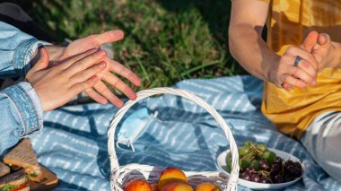 Moldova, Chisinau 'daki salgın sırasında bir parkta, piknik battaniyesinde el dezenfekte eden bir grup arkadaş.