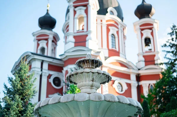 Fountain with falling water in Curchi monasery view from below, trees and church on the foreground, Moldova