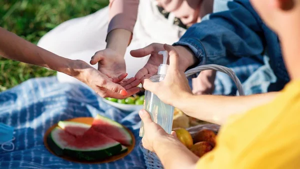 Moldova, Chisinau 'daki salgın sırasında bir parkta, piknik battaniyesinde el dezenfekte eden bir grup arkadaş.