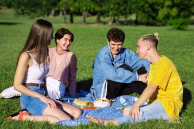 Bir grup arkadaş, Moldova 'nın Chisinau kentindeki salgın sırasında parkta şekerlerle piknik battaniyesinde eğleniyor.