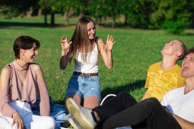 Bir grup arkadaş, Moldova 'nın Chisinau kentindeki salgın sırasında parkta şekerlerle piknik battaniyesinde eğleniyor.