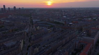 Danimarka 'nın başkenti Kopenhag' da endüstriyel bacalar ve kuleler ile Vesterbro ve Frederiksberg 'in çatıları üzerinde sıcak akşam ışığının hava aracı görüntüsü