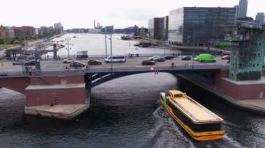 Kopenhag, Danimarka - 4 Ağustos 2025: Köprünün altından geçen ve arka planda tarihi Kopenhag evleri ve kanalları olan bir teknenin insansız hava aracı görüntüsü