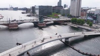 Kopenhag, Danimarka - 4 Ağustos 2025: Eğri yayanın ve Kopenhag limanına yayılan bisiklet köprüsünün hava aracı görüntüsü, Langebro köprüsünün arkasında