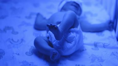 Yeni doğmuş bir bebeğin beşik yatağında hareketli, mavi ışıklı bebek bezi giymiş,