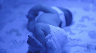 Yeni doğmuş bir bebeğin beşik yatağında hareketli, mavi ışıklı bebek bezi giymiş,