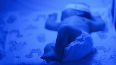 Yeni doğmuş bir bebeğin beşik yatağında hareketli, mavi ışıklı bebek bezi giymiş,