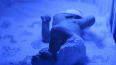 Yeni doğmuş bir bebeğin beşik yatağında hareketli, mavi ışıklı bebek bezi giymiş,