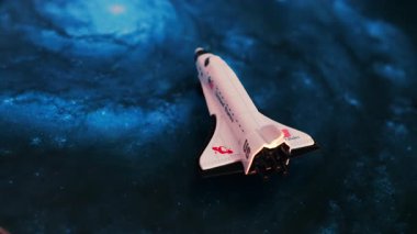 Mavi kozmik bir arka plana yerleştirilmiş minyatür bir oyuncak uzay mekiğine yakın çekim