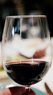 Zengin yakut rengini gösteren bir bardak kırmızı şarabın kıvrımlarını kapatın. Dikey