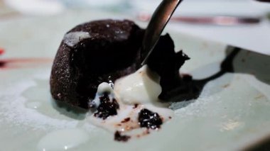 Eritilmiş vanilyalı dondurmayla servis edilen zengin bir çikolatalı lav keki.