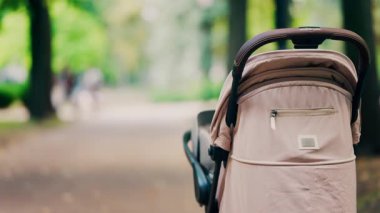 Parktaki bir orman yolunda park etmiş bej bir bebek arabası.