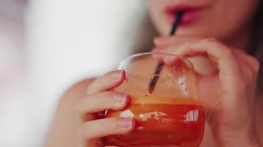 Pipetle taze havuç suyu yudumlayan bir kadının yakın çekimi.