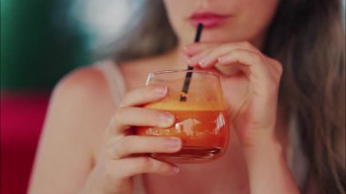 Pipetle taze havuç suyu yudumlayan bir kadının yakın çekimi.