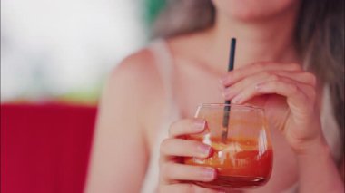 Pipetle taze havuç suyu yudumlayan bir kadının yakın çekimi.