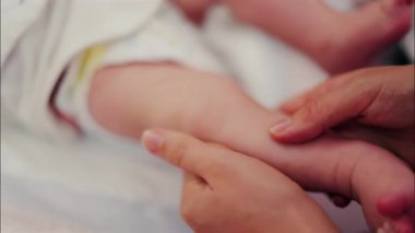 Bebeğin bacaklarına masaj yapan bir ebeveynin ellerini kapat.