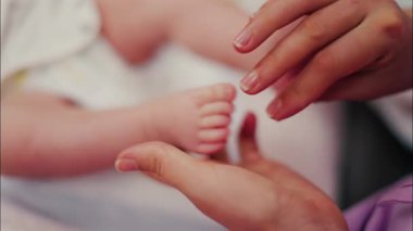 Bebeğin bacaklarına masaj yapan bir ebeveynin ellerini kapat.